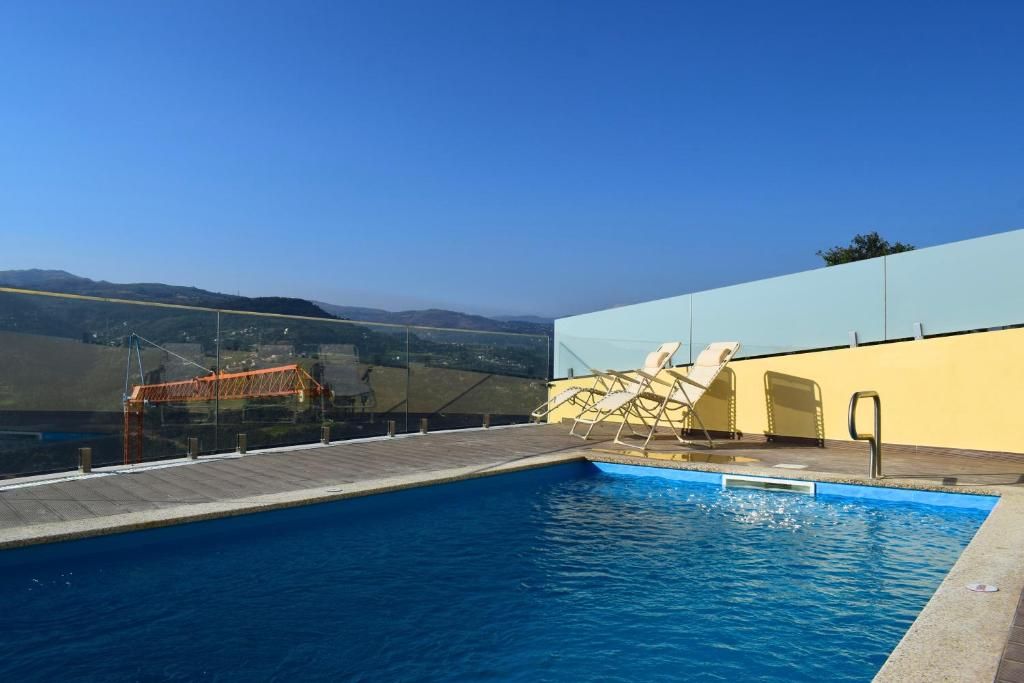Ein Schwimmbecken mit Holzterrasse, Liegestühlen und einer Glasbarriere.