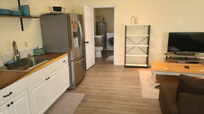 A compact kitchen with a refrigerator, sink, and a washing machine in the background. - Tremendous 1-bedroom house with AC in charming Grants Pass (Grants Pass)