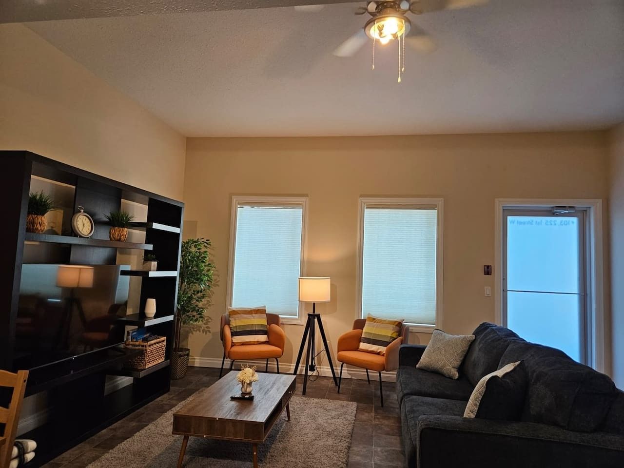 A living room with a sofa, two armchairs, a coffee table, a TV, and a bookshelf.