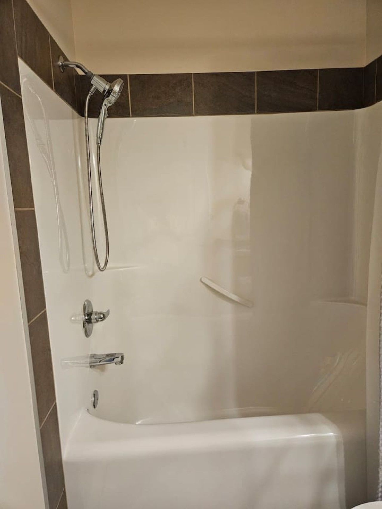 Un baño moderno con una bañera blanca, un cabezal de ducha manual y un grifo empotrado.