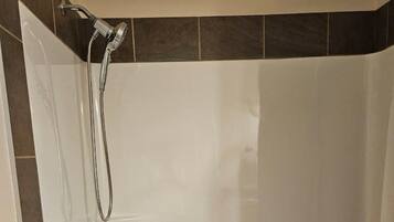 Un baño moderno con una bañera blanca, un cabezal de ducha manual y un grifo empotrado.