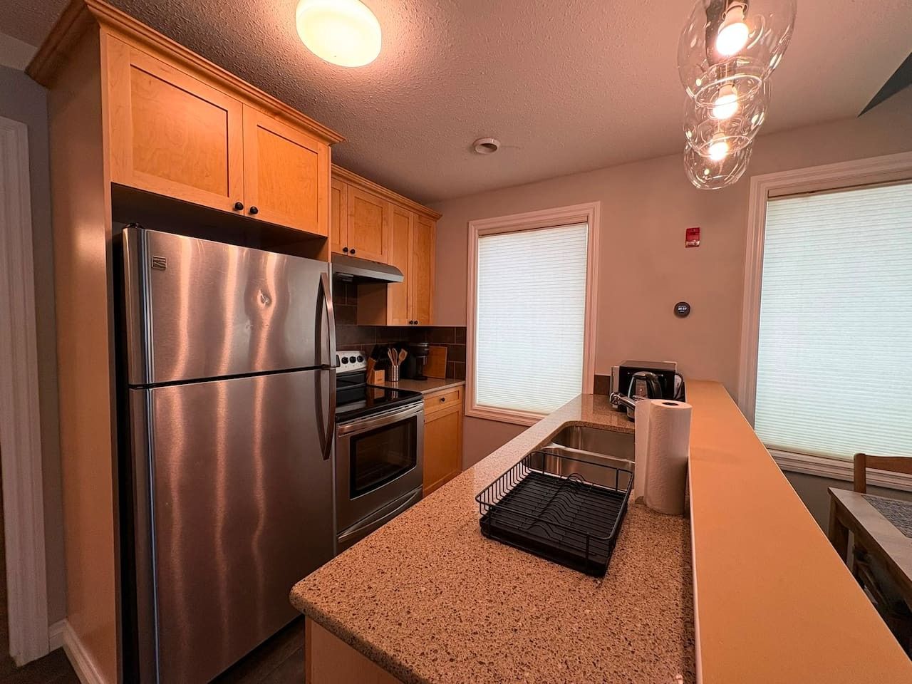A modern kitchen with stainless steel appliances, wooden cabinets, and a granite countertop.