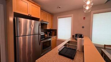 A modern kitchen with stainless steel appliances, wooden cabinets, and a granite countertop.