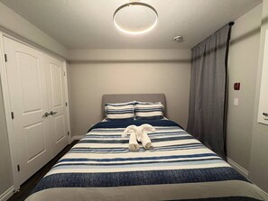 Ein Hotelzimmer mit Bett, Kopfteil, Tür und Vorhang.