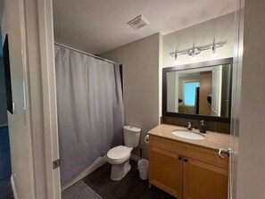 Ein Badezimmer mit Toilette, Duschvorhang, Waschbecken und Spiegel.