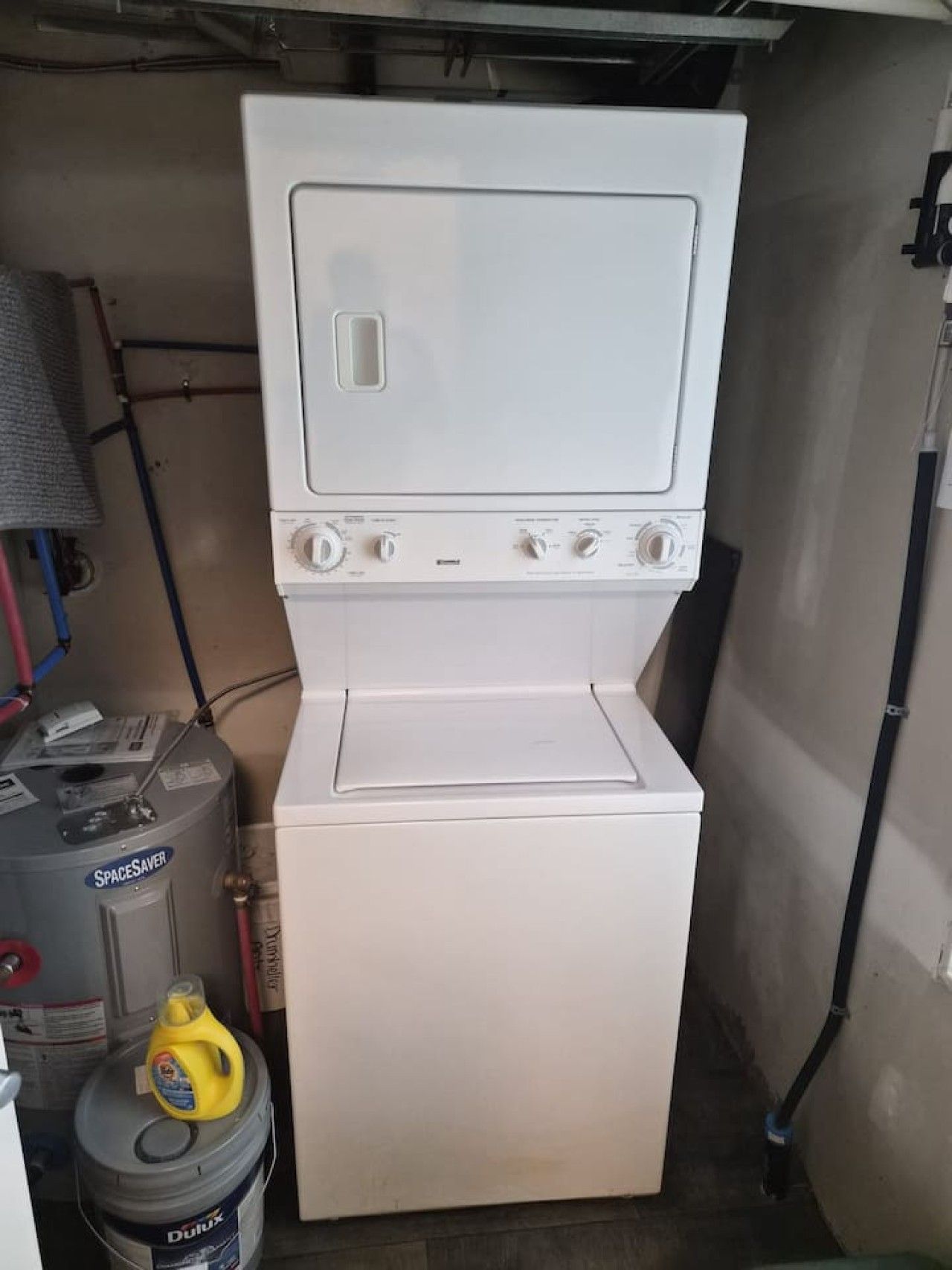 A compact laundry room with a white washer and dryer, a water heater, and a storage tank.