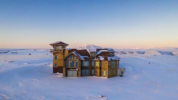 A wooden cabin with multiple rooms and a large window, surrounded by snow-covered landscape.