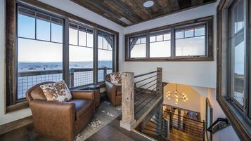 Una habitación con amplios ventanales, chimenea y una escalera.