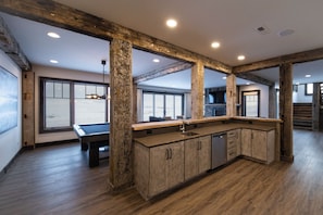 A spacious kitchen with wooden beams, a central island, and a view to the outside.