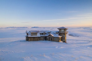 A wooden cabin with a tower, surrounded by snow-covered landscape.