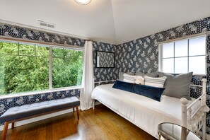 A bedroom with a large window, a bed with multiple pillows, a bench, and patterned wallpaper. - Private, stylish townhouse in Prime Capitol Hill, Seattle location (Seattle)