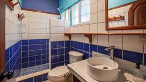 Un baño con lavamanos blanco, inodoro y zona de ducha.