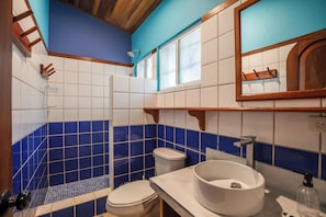 A bathroom with a white sink, a toilet, and a shower area. - Rick's Place (Guiones)