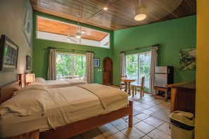 Een kamer met twee bedden, een eethoek en uitzicht op groen.