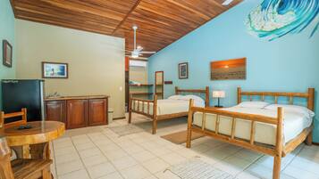 Una habitación con dos camas de madera, un escritorio con una silla, un televisor y un ventilador de techo.
