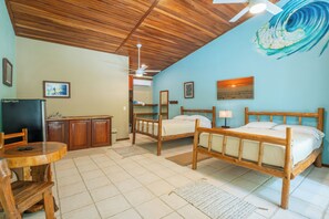 A room with two wooden beds, a desk with a chair, a television, and a ceiling fan. - Rick's Place (Nosara)