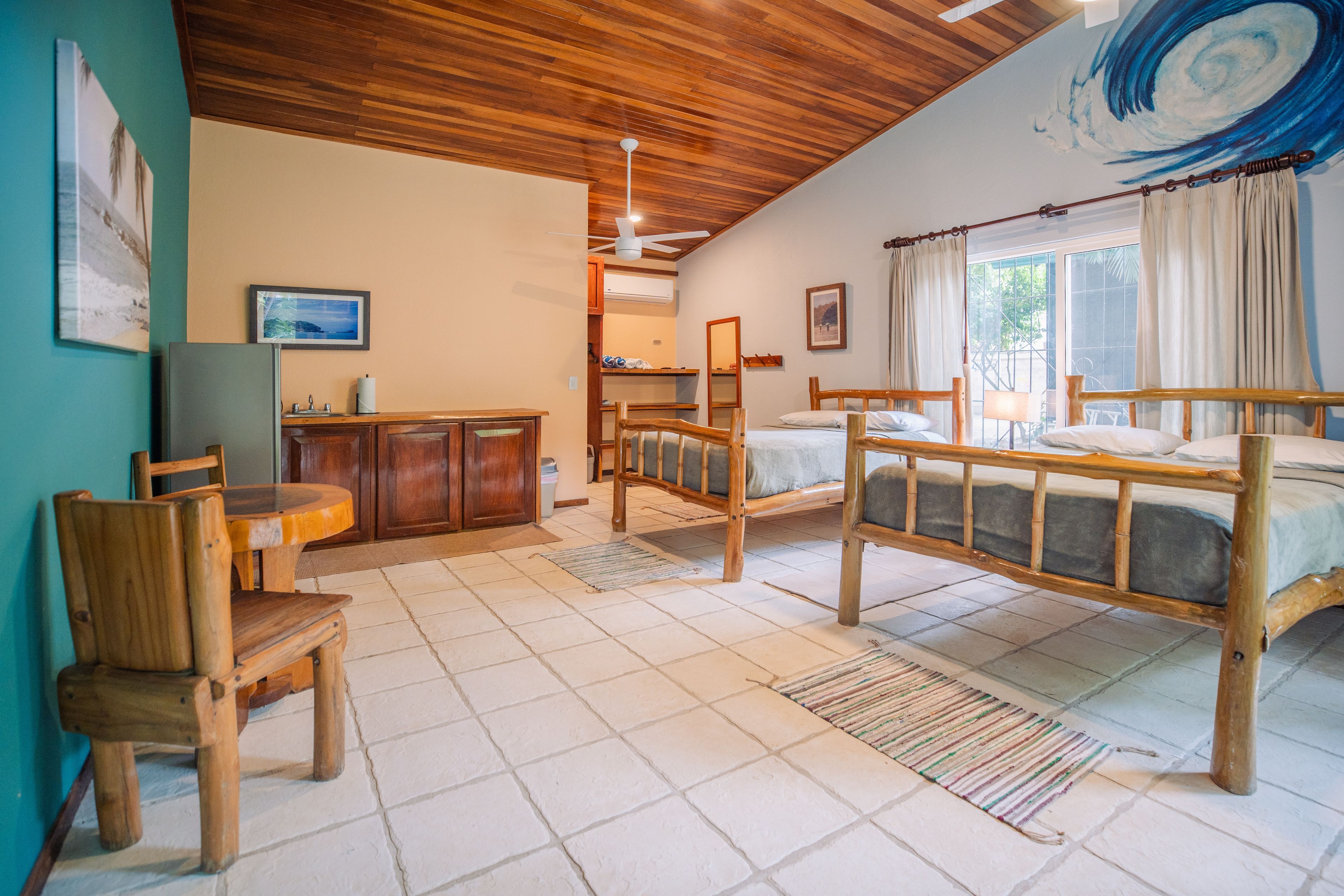 A room with a wooden ceiling, a bed, a desk, and a chair.
