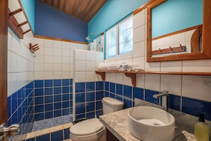 Een badkamer met een wit toilet, een wastafel met een marmeren blad en blauwe betegelde wanden.