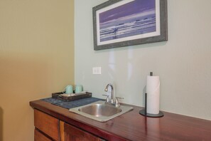 A bathroom with a sink, a towel dispenser, and a framed picture on the wall. - Rick's Place (Nosara)