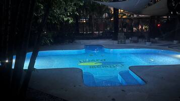 Una piscina con diseño de mosaicos y una zona con sombra.