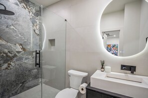 Ein modernes Badezimmer mit Duschkabine aus Glas, Toilette und Waschtisch mit Spiegel.