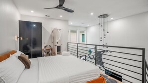 Une chambre moderne comprenant un lit, un bureau, une chaise, une armoire et un balcon avec une rambarde.