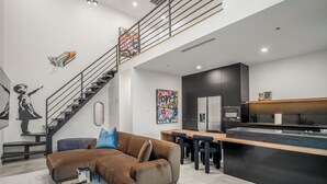 Un espace de vie moderne comprenant un escalier, un canapé, un coin repas et une cuisine.