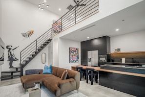 Ein modernes Wohnzimmer mit Treppe, einer Couch, einem Essbereich und einer Küche.