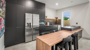 Une cuisine moderne dotée d’un îlot central, de meubles de rangement aux couleurs sombres et d’un grand réfrigérateur.