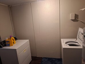 Een wasserette met een wasmachine, droger en flessen wasmiddel.