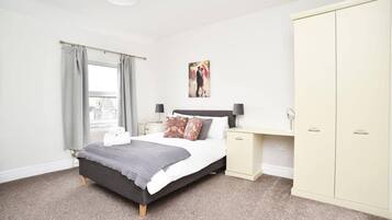 A bedroom with a bed, bedside tables, a wardrobe, and a window with curtains.