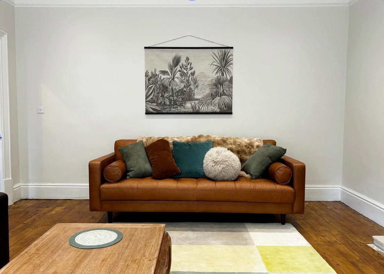 A living room with a brown leather sofa, a coffee table, and a wall-mounted picture.