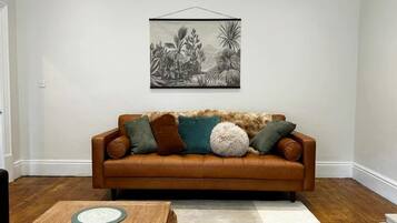 A living room with a brown leather sofa, a coffee table, and a wall-mounted picture.