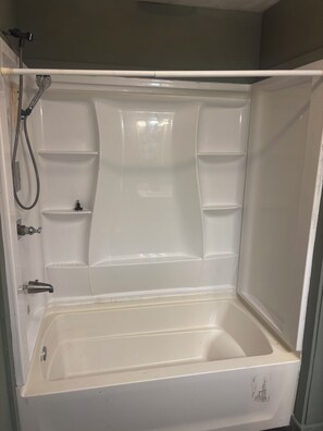 A white bathtub with a shower head and control knobs.