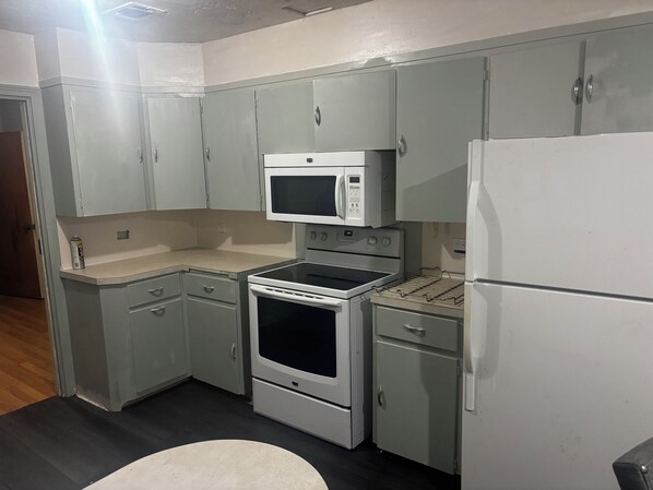 A compact kitchen with a microwave, oven, and refrigerator.