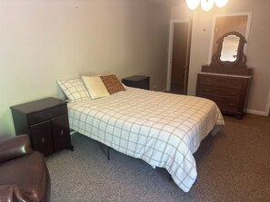 A bedroom with a bed, nightstands, a dresser, and a mirror.