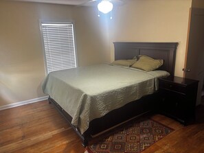 A bedroom with a bed, nightstand, and a patterned rug.