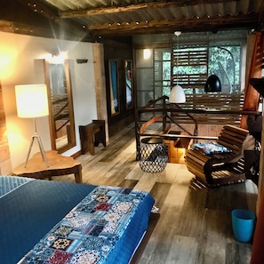 A room with a bed, a desk, a chair, a lamp, and a window with blinds.