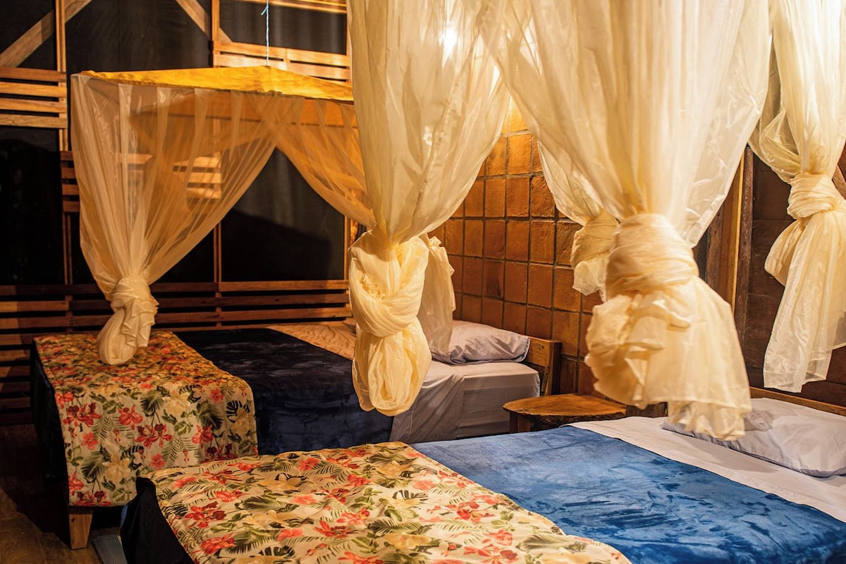 A room with a canopy bed, a smaller bed, and a bench.