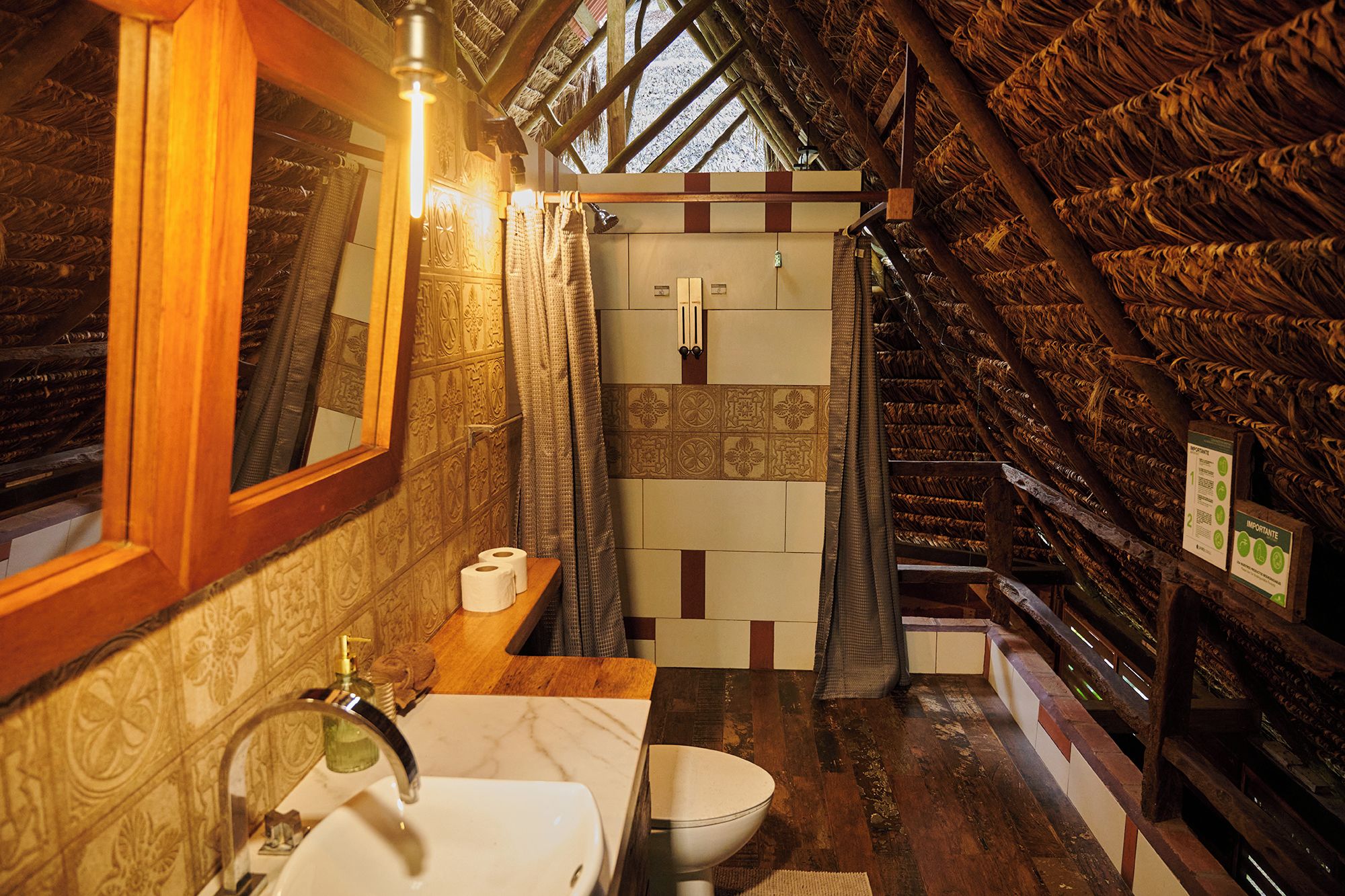 Un baño con techo de madera, un lavabo, un inodoro y una zona de ducha.