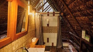 Een badkamer met een houten plafond, een wastafel, een toilet en een douchehoek.