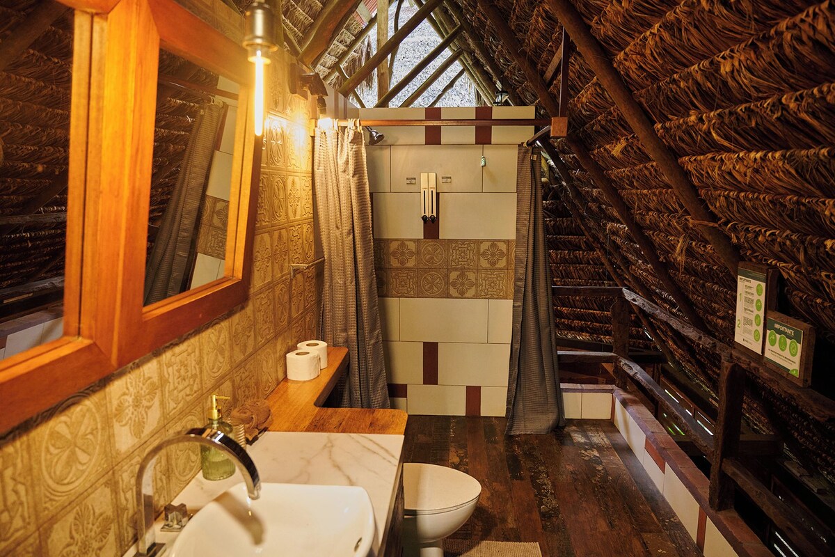 A bathroom with a wooden ceiling, a sink, a toilet, and a shower area.