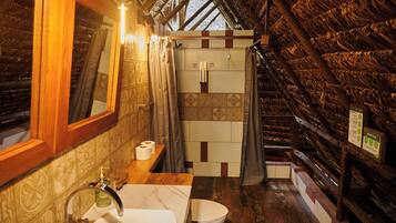 Un baño con techo de madera, un lavabo, un inodoro y una zona de ducha.