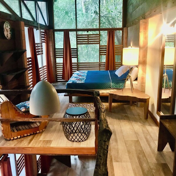 A room with a bed, a sofa, a lamp, and a wooden table.