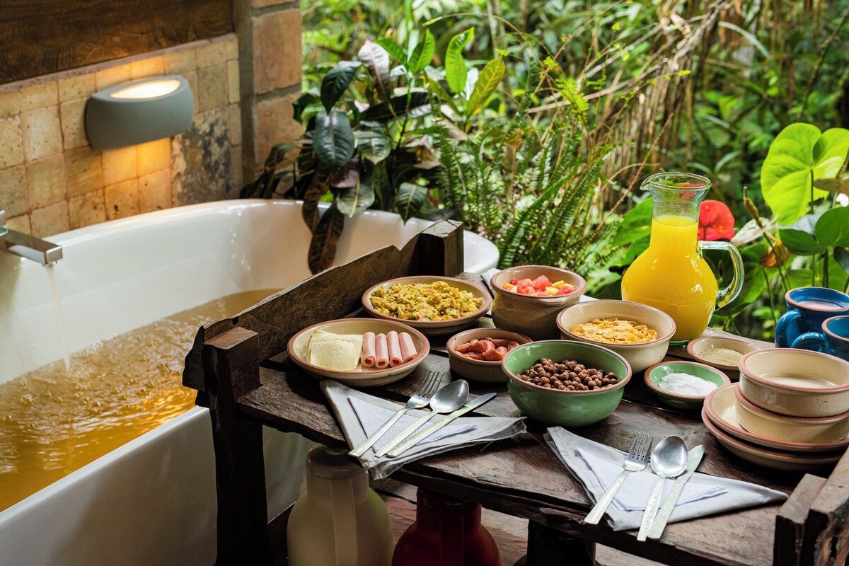 A breakfast setup with a variety of dishes, a jug of orange juice, and a bathtub filled with water.