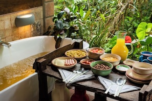 A breakfast setup with a variety of dishes, a jug of orange juice, and a bathtub filled with water.