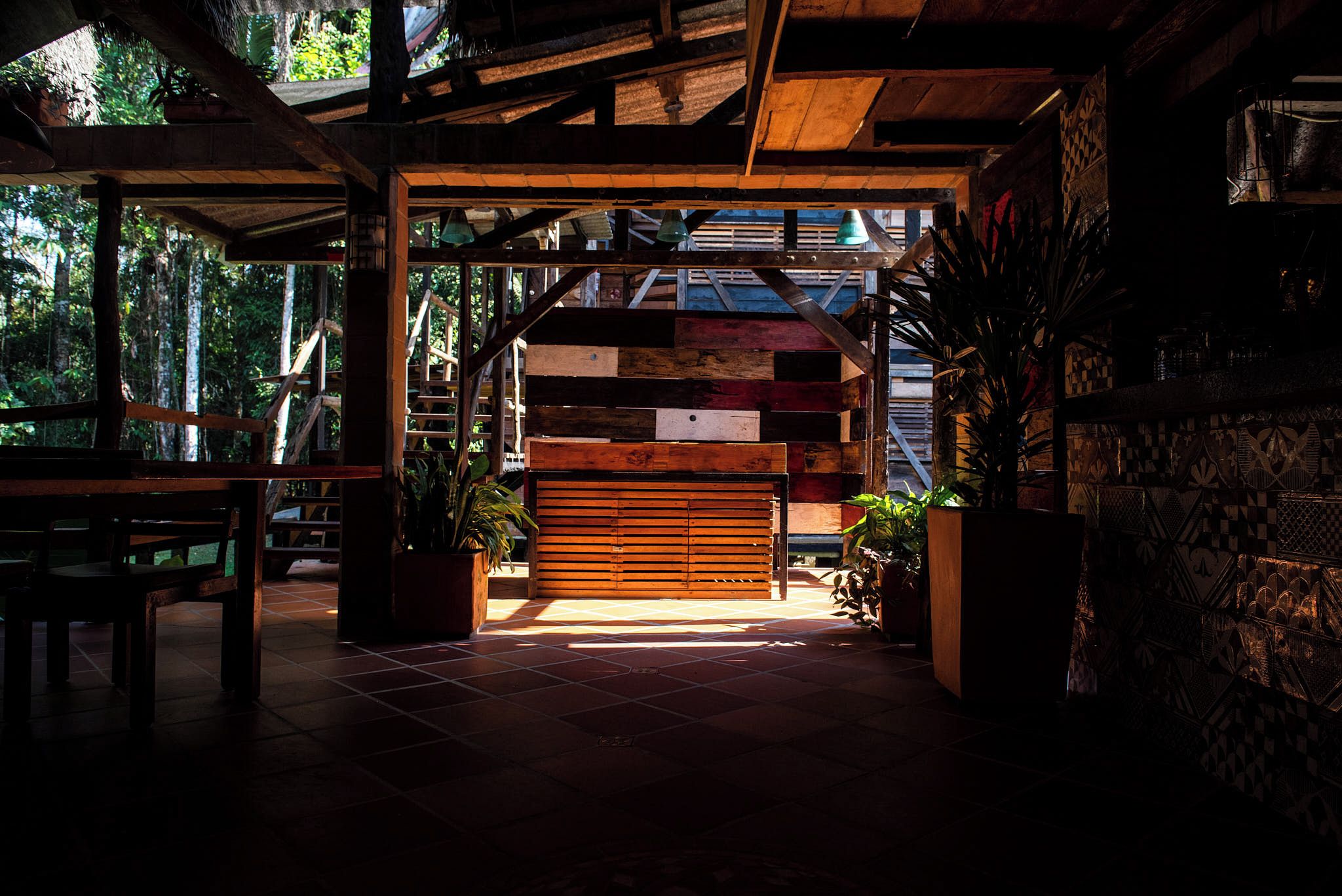 An interior space with a wooden bench, a tiled floor, and a view of the outdoors.