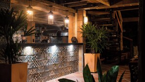 Een bar met een betegelde spatwand, hangende pendelverlichting en potplanten.