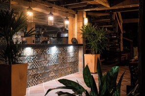 A bar area with a patterned tile backsplash, hanging pendant lights, and potted plants. - Cuybeno Jamu Lodge  (Sucumbíos)
