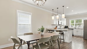 A modern kitchen with white cabinets, a central island, and pendant lighting. - Bear's Den - 2.3 mi to DT-Direct MTB Trail Access (Bentonville)
